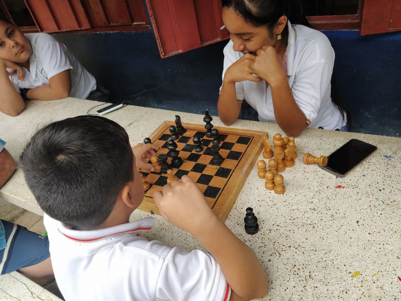 Nina observando un tablero de ajedrez en una actividad escolar