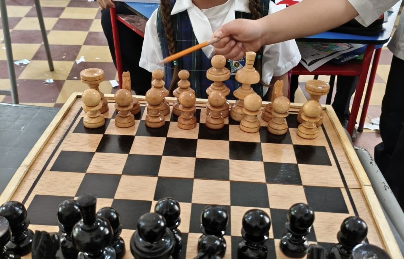 Nina frente a un tablero de ajedrez en un entorno escolar