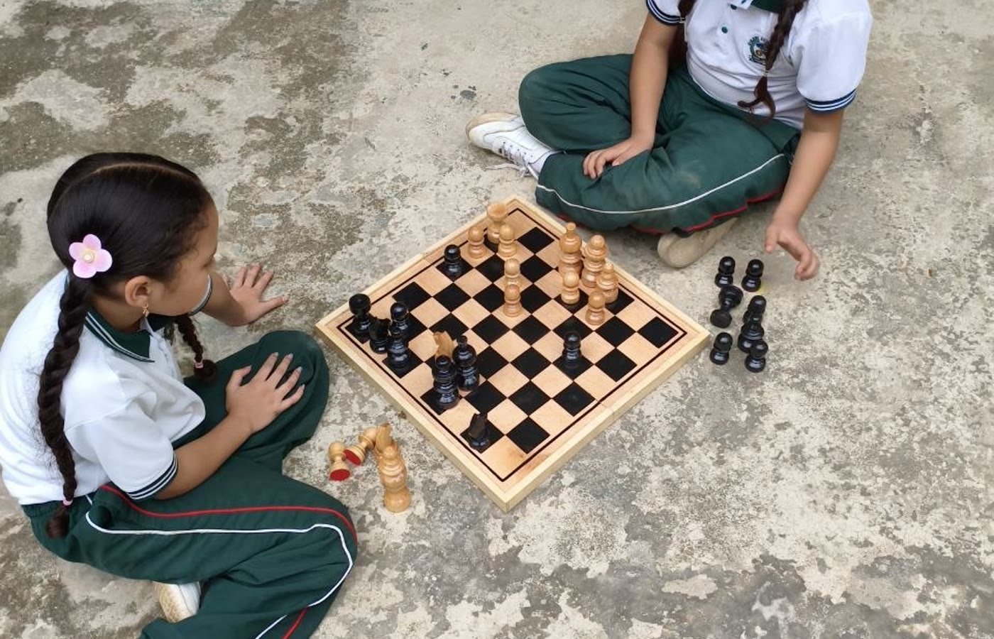 Dos ninas jugando ajedrez en un patio escolar